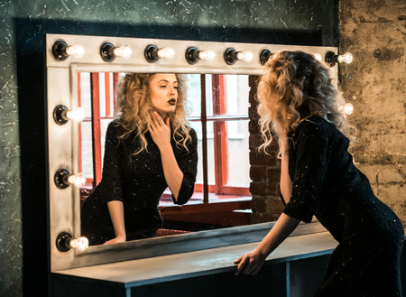 Beautiful fashion blond woman posing near the mirrorの写真素材