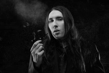 portrait of a fashionable male model with long hair over dark background. studio shotの写真素材