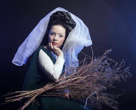 girl in medieval dress  with bunch of sticks in smokeの写真素材