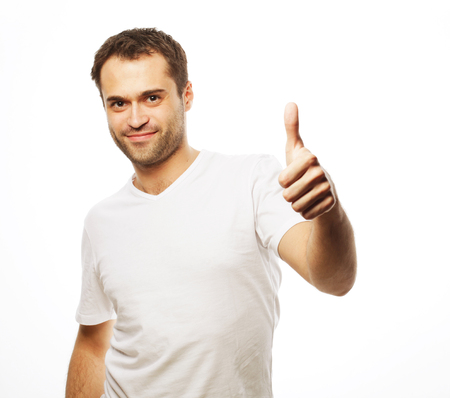 life style  and people concept: Happy handsome man wearing white t-shirt showing thumbs up over isolated backgroundの写真素材