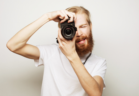 Travel, technology and life style concept: young bearded  photographer taking pictures with digital camera.の写真素材