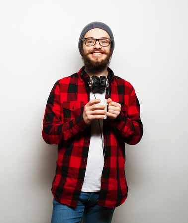 food, happiness and people concept: young bearded man with a cup of coffee against grey backgroundの写真素材