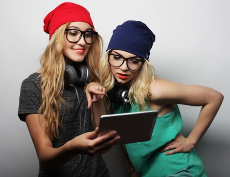 two hipster girls friends use digital tablet, studio shot over gray vackgroundの写真素材