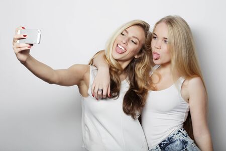 two young funny women taking selfie with mobile phone