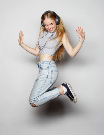 smiling young woman jumping in air over gray backgroundの写真素材