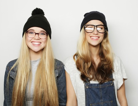 Two young girl friends standing together and having fun. Looking at camera.の写真素材