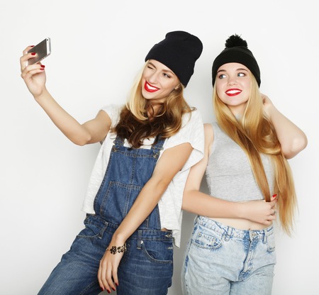 two young funny women taking selfie with mobile phoneの写真素材
