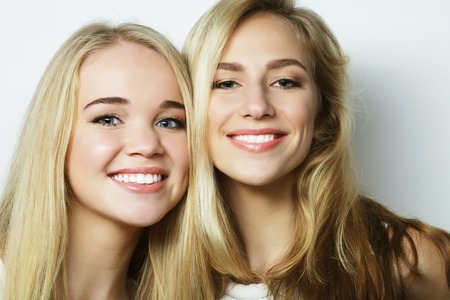Two young girl friends standing together and having fun. Looking at camera.の写真素材