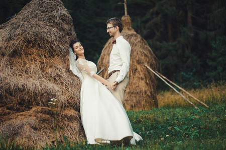 Beautiful wedding in the mountains, a young happy couple near the hayloft.の写真素材