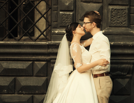 stylish luxury  bride and elegant groom, hugging with tenderness,on the background of the old city Lvivの写真素材