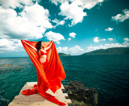Young woman with red skirt and  fabric like a wings. Vogue style.の写真素材