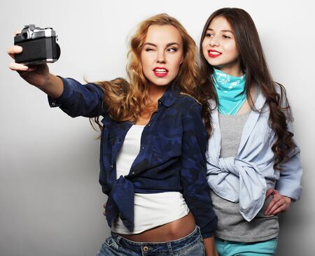 lifestyle and people concept: Happy girls friends taking some pictures, over grey backgroundの写真素材