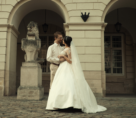 stylish luxury  bride and elegant groom, hugging with tenderness,on the background of the old city Lvivの写真素材