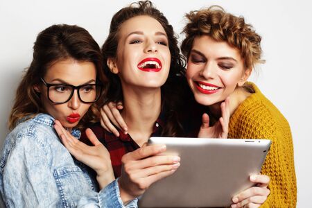 three teen girls friends taking selfie with digital tablet, studio shot over gray backgroundの写真素材