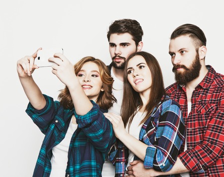 education, technology and people concept: group of students taking selfie with smartphone  over white background.Special Fashionable toning.の写真素材
