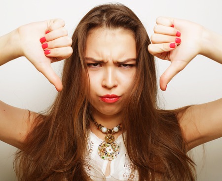 Unhappy woman giving thumbs down gesture looking with negative expression and disapproval.の写真素材
