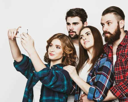 education, technology and people concept: group of students taking selfie with smartphone  over white background.Special Fashionable toning.の写真素材