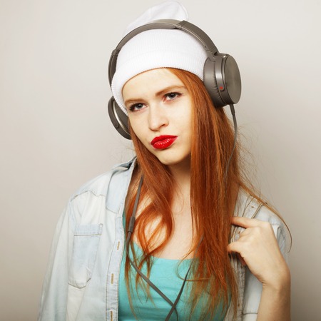 Young redhair woman with headphones listening music.の写真素材