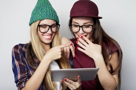 lifestyle and people concept:  two hipster girls friends use digital tabletの写真素材
