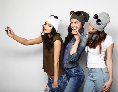friendship, people and technology concept - three happy teenage girls with smartphone taking selfie