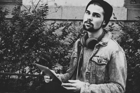man holding a tablet and thinking in the street, black and white pictureの写真素材
