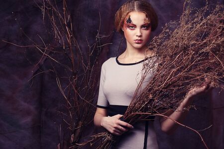 Young woman with bright make up with dry branchesの写真素材