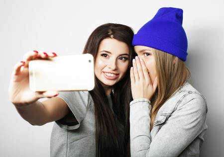 Two teenage girls friends in hipster outfit make selfie on a phone.の写真素材
