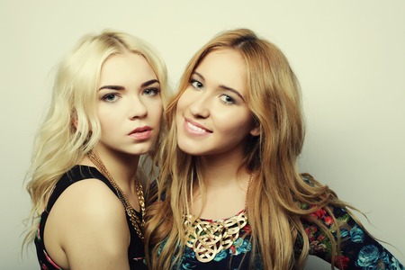 Two girl friends together smiling, studio shotの写真素材