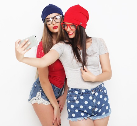 Two teenage girls friends in hipster outfit make selfie on a phone.の写真素材