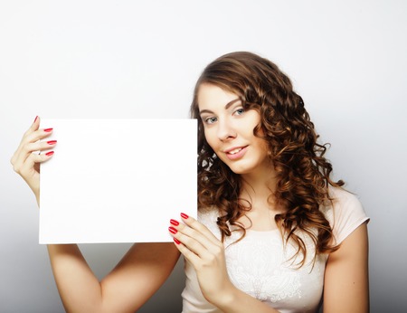 Smiling young casual style woman showing blank signboard, over grey  background isolatedの写真素材