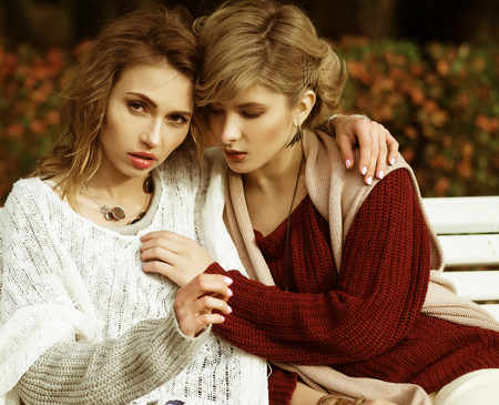 life style, happiness, emotional and people concept: beautiful young women sitting on a bench in the autumn parkの写真素材
