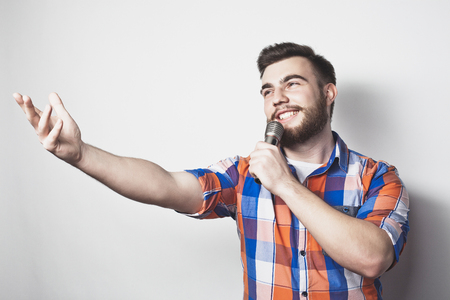 young singer man  with microphone over grey backgroundの写真素材