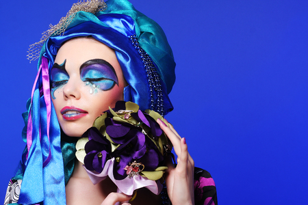 Young woman with creative make up holding a bouquet of jewelryの写真素材