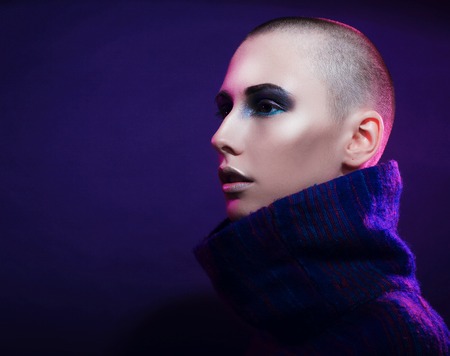 Young fashion model posing in studio. Bald. Bright make up. Over Pink Background.