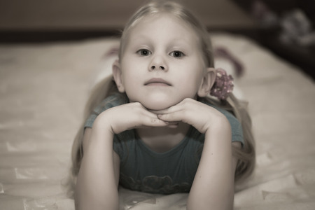 Little blonde girl on the bedの写真素材