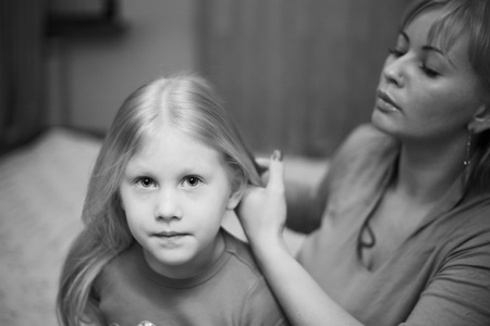 mother combing her daughters hairの写真素材