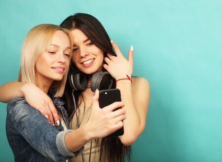 Two  girls friends in hipster outfit make selfie on a phone.の写真素材