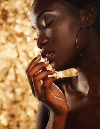 portrait of sensual young african woman against golden backgroundの写真素材