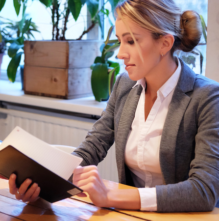 Young businesswoman  sitting at table in coffee shop and readingの写真素材