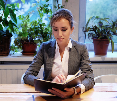 Young businesswoman  sitting at table in coffee shop and reading