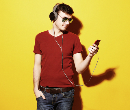 Music! Young man wearing headphones and holding mobile phone.の写真素材