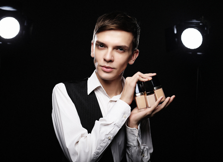 Young male make up artist posing with foundation for make-upの写真素材