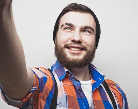 Close up portrait of a cheerful bearded man taking selfie over white backgroundの写真素材