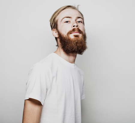 Portrait of a young bearded man in a white T-shirtの写真素材