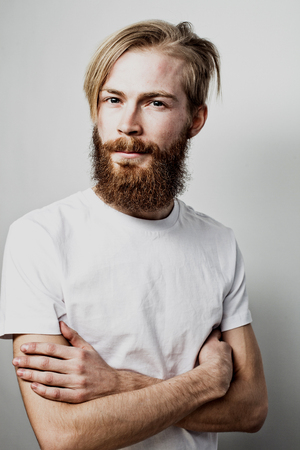 Lifestyle and people concept: Young bearded guy crossing his arms over white backgroundの写真素材
