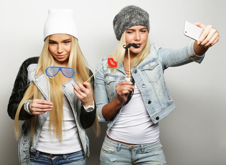 Life style, happiness, emotional and people concept: two hipster girls taking photo. Happy selfie.の写真素材