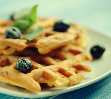 Homemade waffles with blueberries in plate on wooden tableの写真素材
