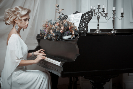 Beautiful young bride playing the pianoの写真素材