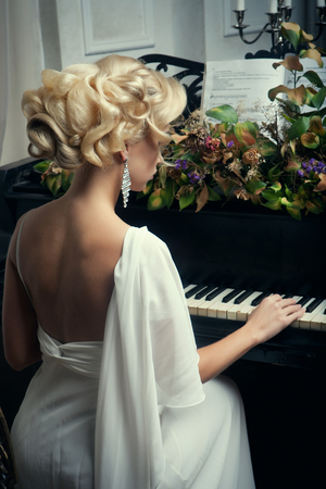 Beautiful young bride playing the pianoの写真素材