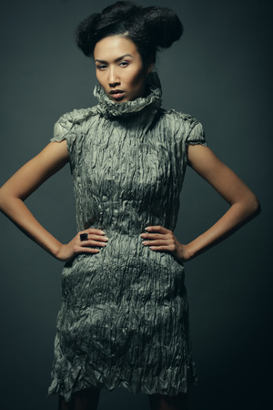 Beauty and fashion concept: young Asian fashion model in grey dress against black backgroundの写真素材